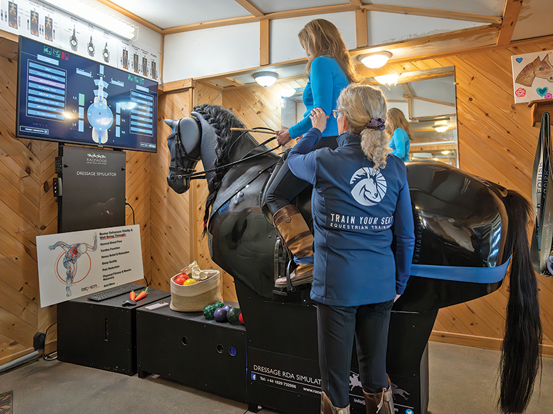 Alt text: Susan Cruickshank coaching rider position and leg alignment on RooElla horse simulator.